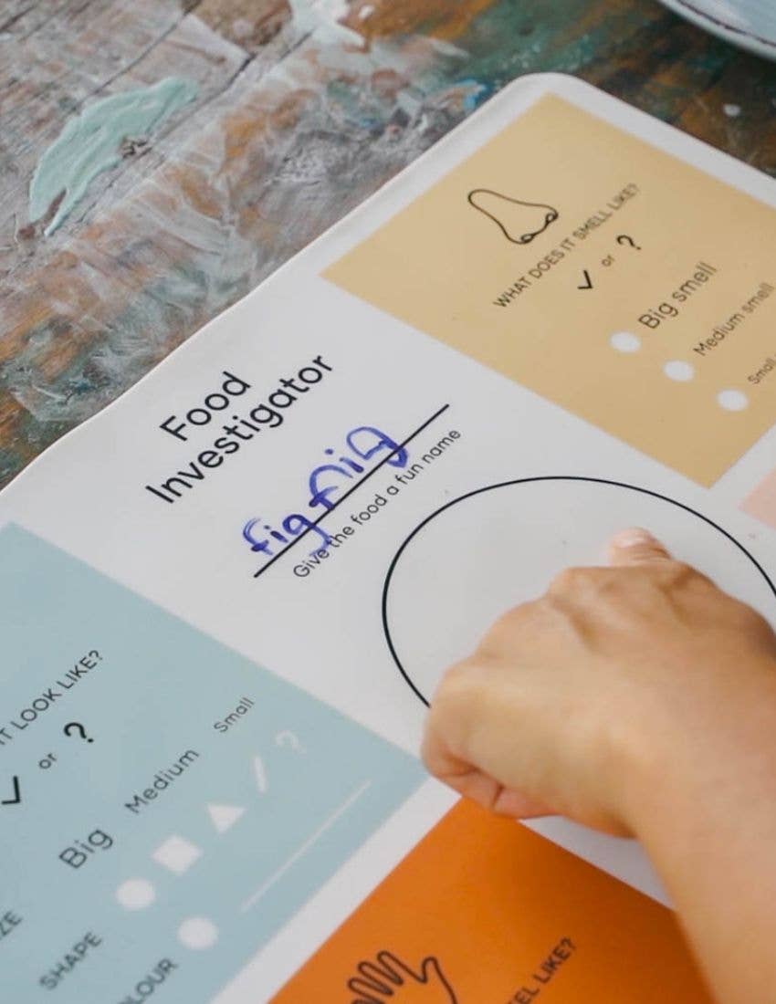 Person interacting with a 'Food Investigator' worksheet on a textured surface