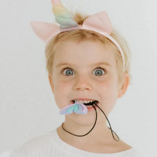 Child wearing a colorful headband and holding a toy with a white background